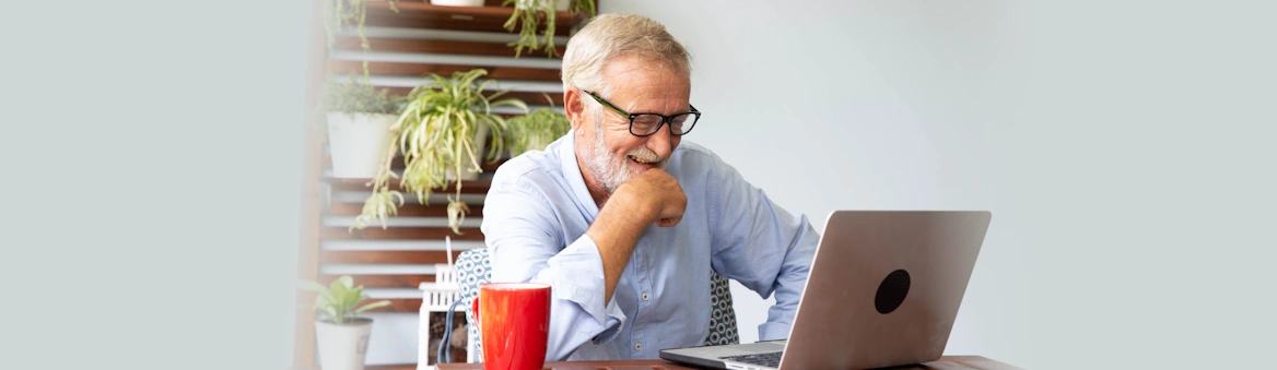 Life Assure Senior Researching Online With Laptop Buying Advice Hero